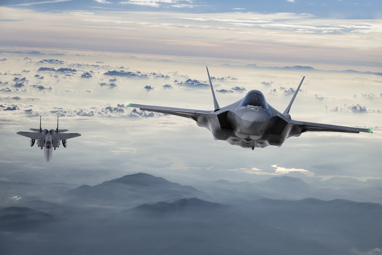 Two fighter jets flying above the clouds, representing the aerospace and defense programs a manufacturing intelligence platform supports